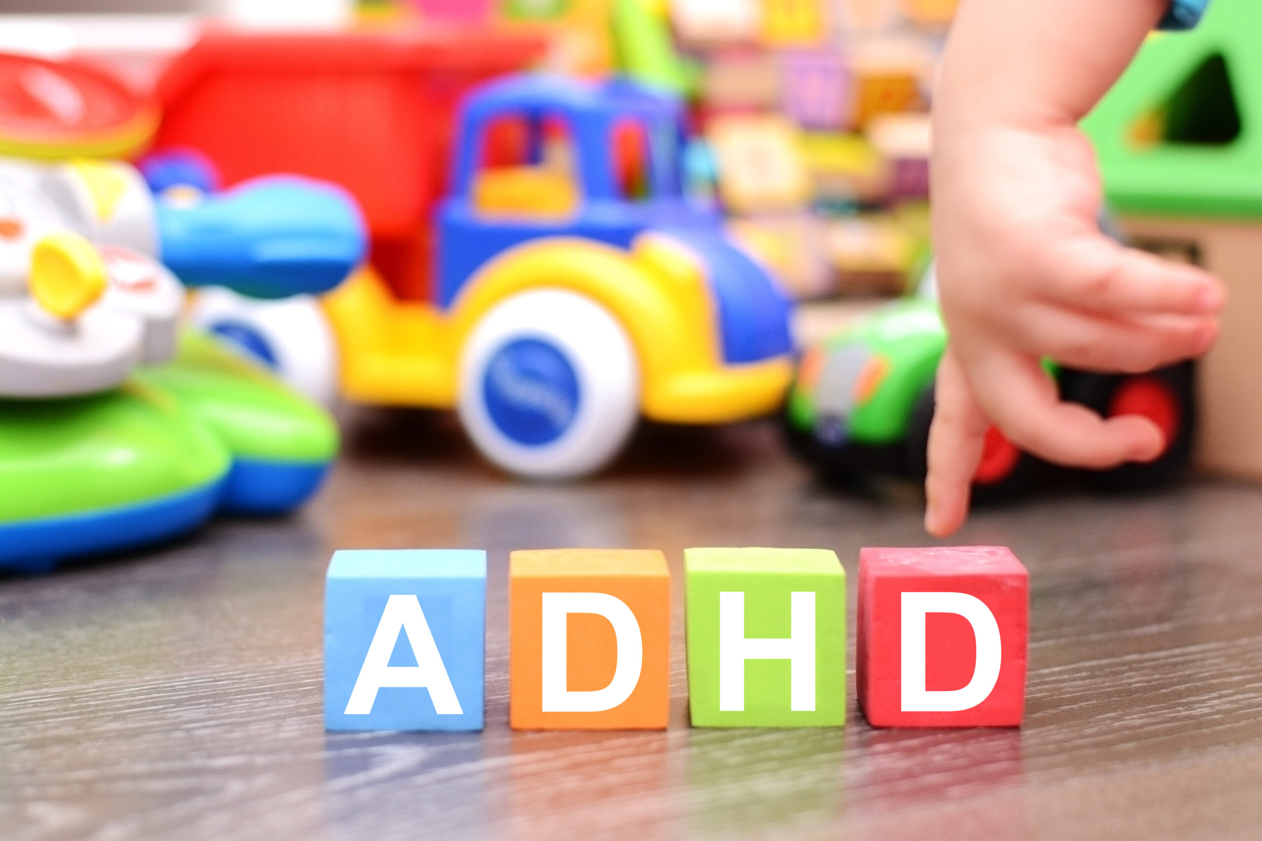 attention deficit hyperactivity disorder or adhd concept with toddler hand touching colored cubes against toys